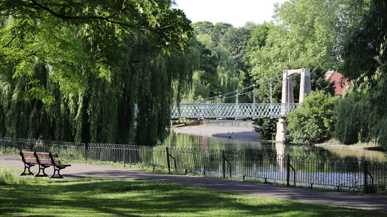 A beautiful view from the shore of a bridge over the River Lea in the Wardown Park in England
