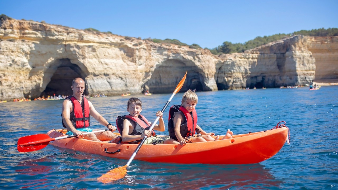 Children, enjoying Benagil, Portugal. Benagil Cave inside Algar de Benagil, famous sea cave in Algarve coast, Lagoa. Happy family on a canoe trip